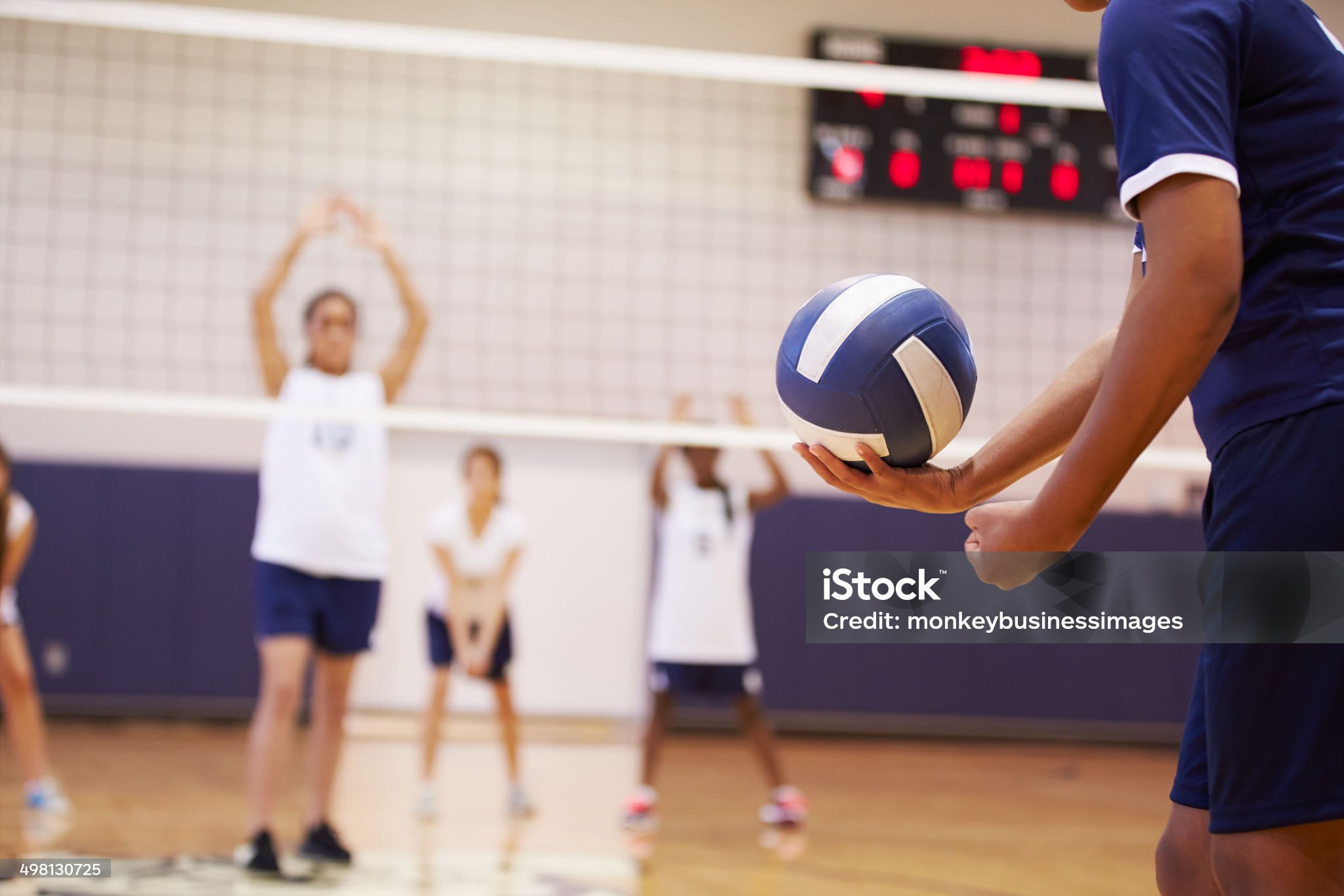 High School Volleyball Match In Gymnasium With Ball